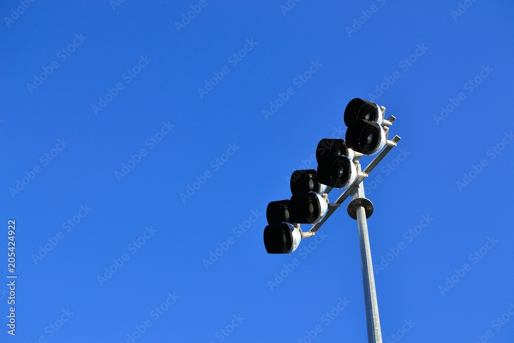 Image of sports lighting during the day with blue sunny sky that can be used to advertise a spotlight or highlight for services, people, or places.