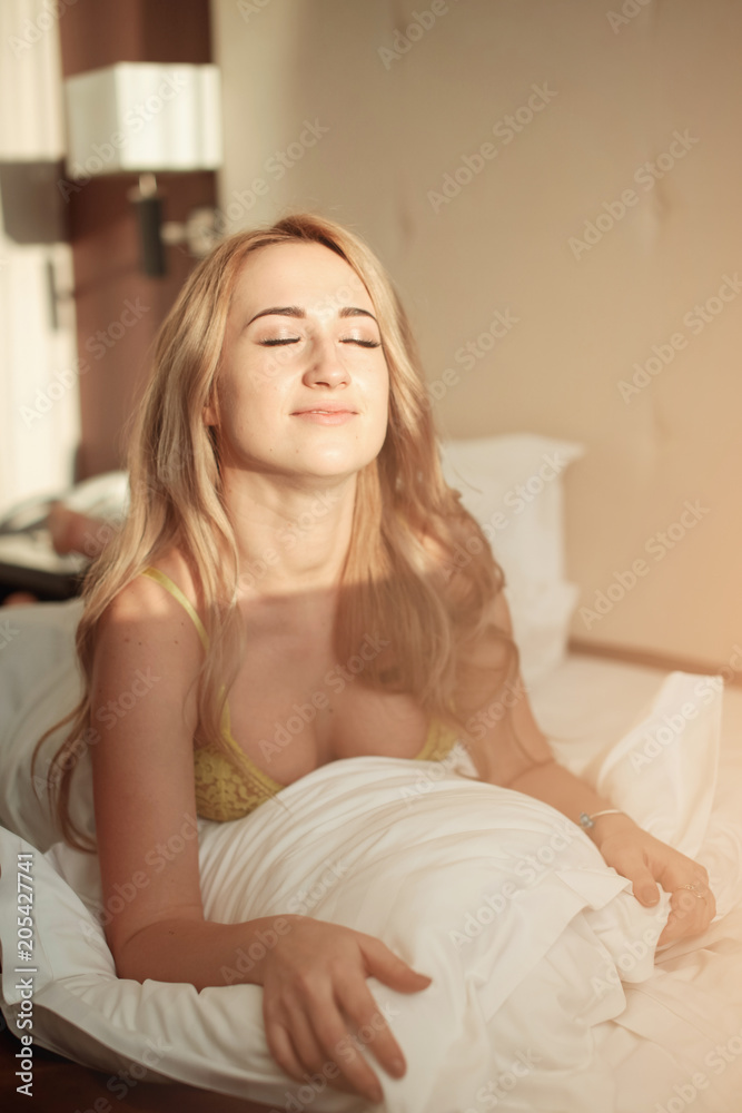 Pretty young woman on bed in modern apartment smiling after wake up Pretty young woman on bed in modern apartment smiling after wake up