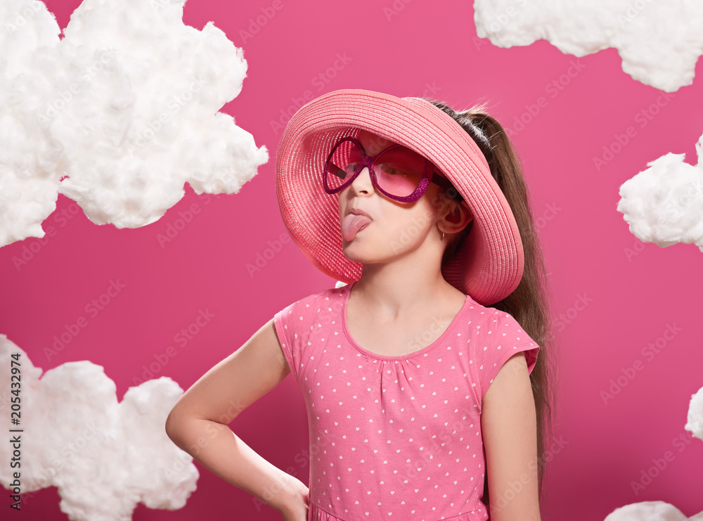 fashionable girl posing on a pink background with clouds, pink dress and hat fashionable girl posing on a pink background with clouds, pink dress and hat