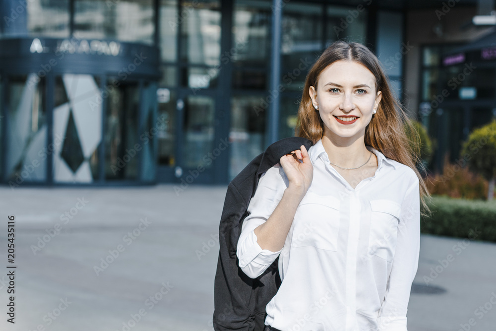 Fototapeta premium A business woman goes down the street. A girl in a business suit at the office. A wonderful girl in the city.