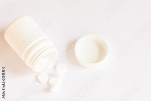 White pills in a bottle on white background.Copy space.Mockup for design.