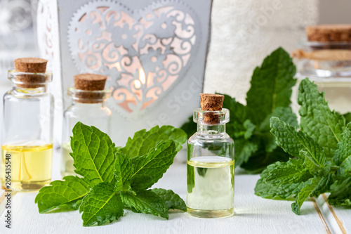 A bottle of essential oil with fresh peppermint leaves