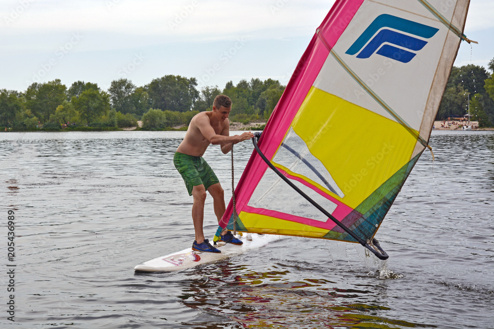 Naklejka premium man stands on the Board in the water windsurfing
