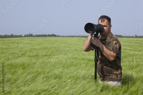 a photographer in a grain field with a telephoto lens