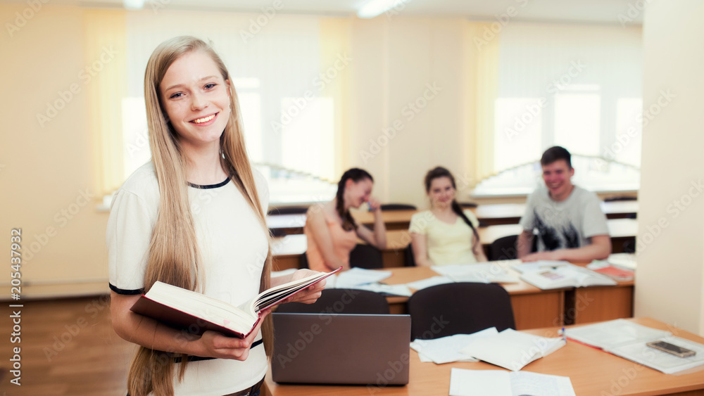 Female college student in a classroom holding a notebook Female college student in a classroom holding a notebook