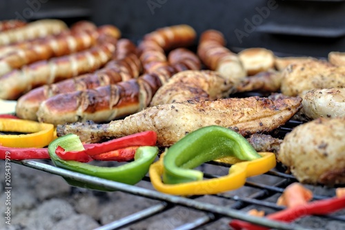  Tasty food, nutrition, culinary and barbecue concept: grilled sausages,chicken thigh and vegetables on a barbeque.