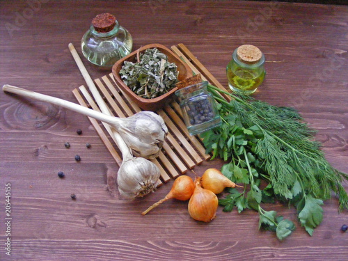 Obraz na plátne Olive oil and sunflower-seed oil with greenery (dill and parsley), juniper berries, onion, dry space on a wooden table