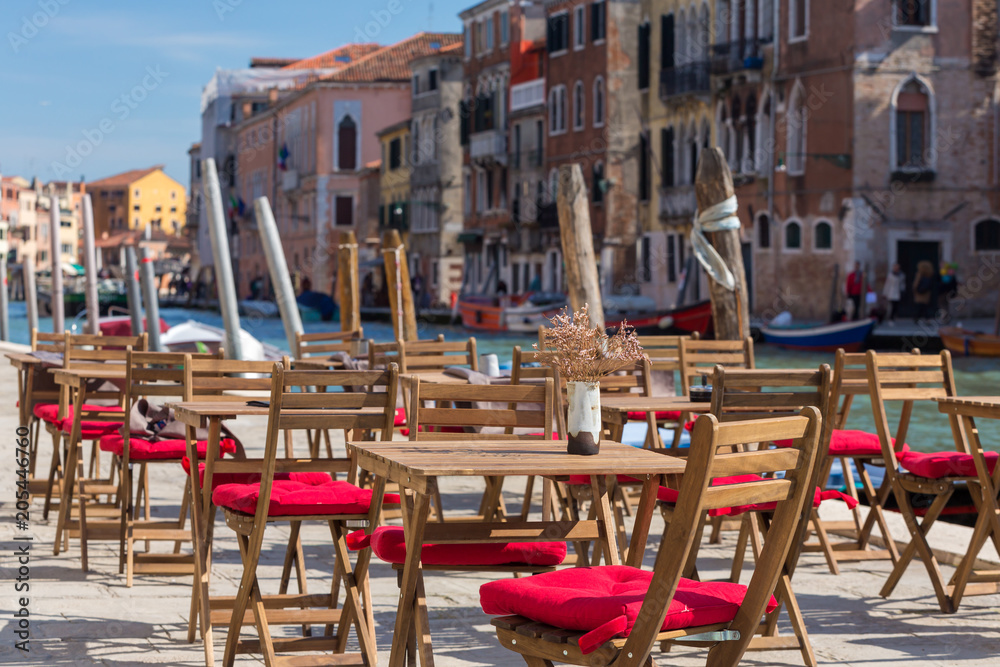 Street view of a cafe terrace with empty tables and chair in Venice, Italy.