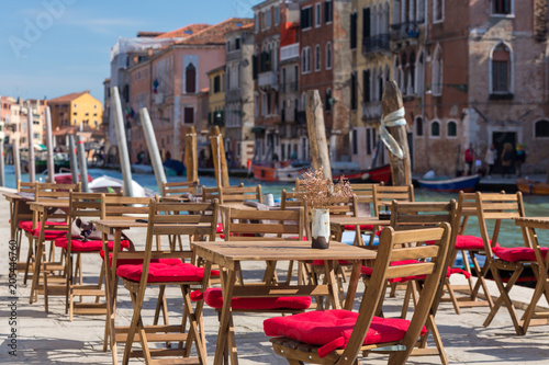 Street view of a cafe terrace with empty tables and chair in Venice, Italy. © Mazur Travel