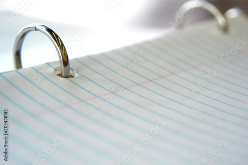 Still life of pen and paper. White college ruled paper with blue lines in a three ring binder. Lined paper in a binder reading to take to school and take notes on. Paper for taking notes on in class.