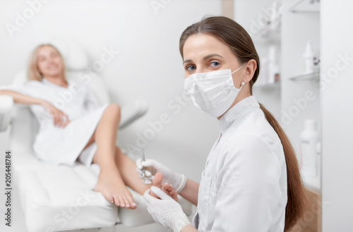 Podiatrist in mask on face looking at camera and working.