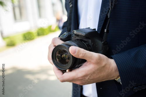 partial view of photojournalist in formal wear holding photo camera
