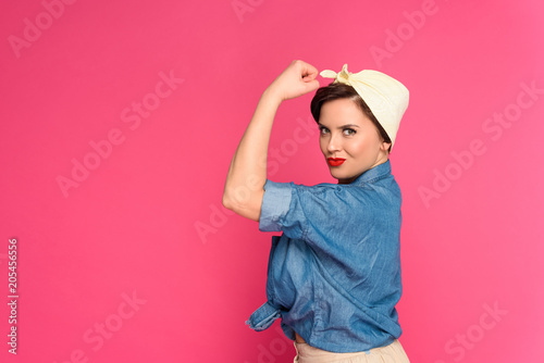 beautiful size plus pin up woman showing muscles and smiling at camera isolated on pink photo