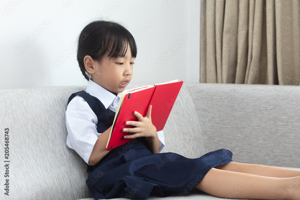 Asian Chinese little girl sitting on the sofa reading book Asian Chinese little girl sitting on the sofa reading book