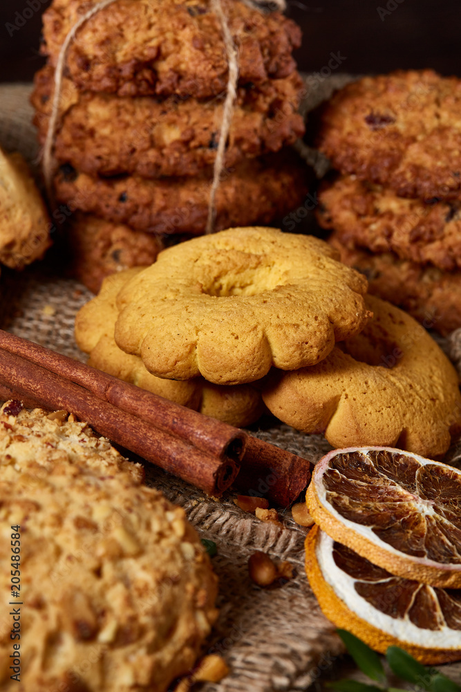 Fototapeta premium Conceptual composition with assortment of cookies and cinnamon on a wooden barrel, selective focus, close-up