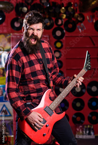 Guitarist on shouting face playing electric guitar on stage