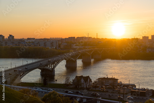 View from the high on Nizhny Novgorod city in Russia, Kanavinsky Bridge over the Oka River at sunset, moving cars on the bridge and on the road photo