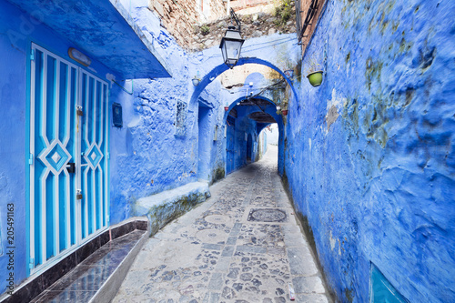 street tunnel with blue walls and street lighter in old moroccan city © sergejson