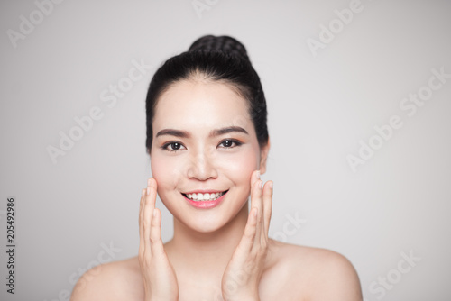 Happy smiling beautiful asian woman touching her face.