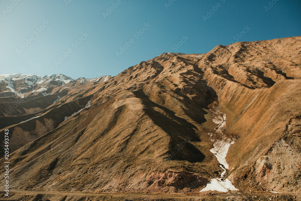 mountainous rocky ridge against blue sky sunbeams