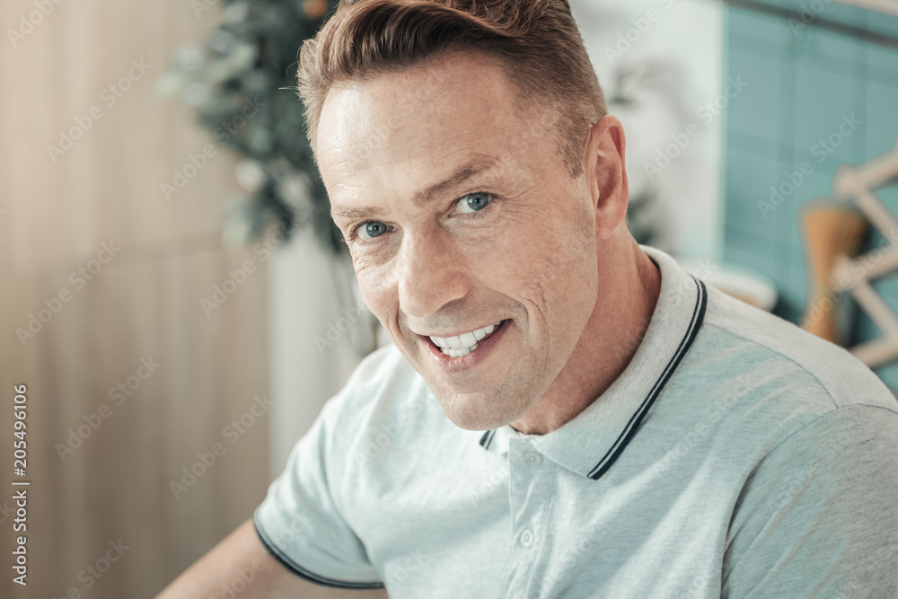 Obraz premium Pleasant smile. Handsome young man demonstrating his emotions and raising eyebrow while watching you