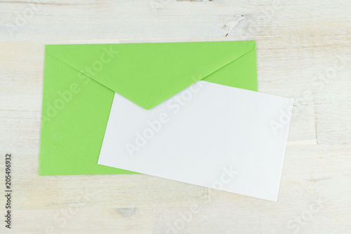 Green envelope with blank letter, wooden background