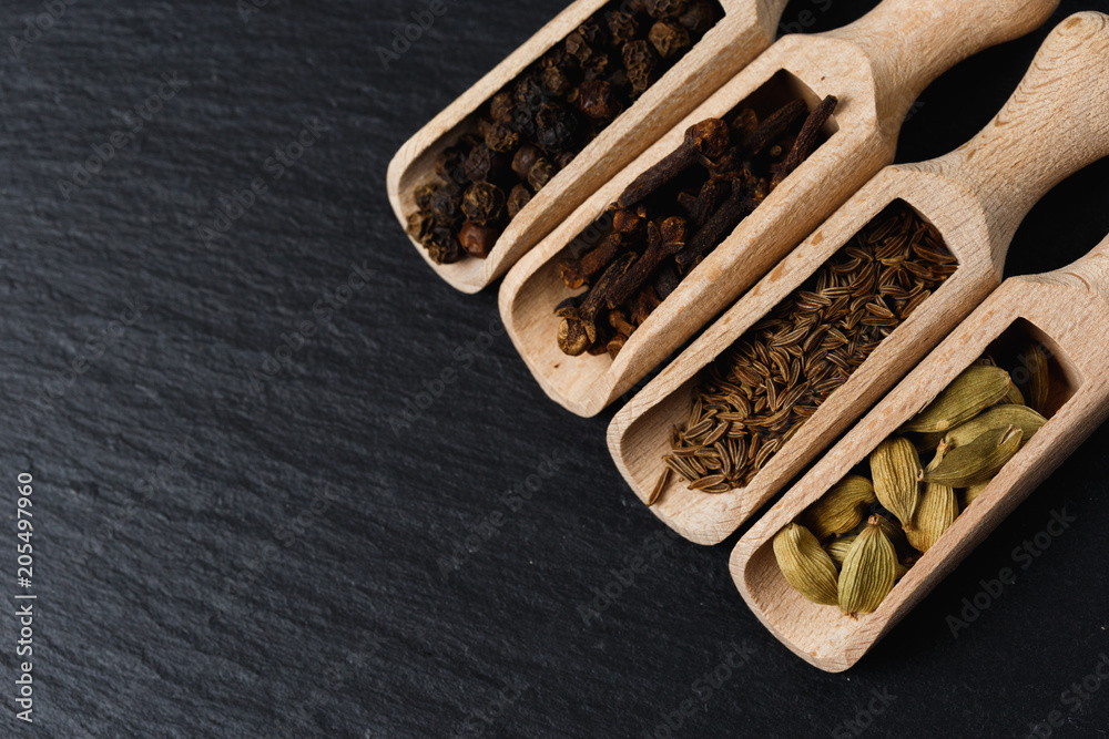 Various of spices and herbs in wooden spoons. Flat lay of spices on black stone Various of spices and herbs in wooden spoons. Flat lay of spices on black stone