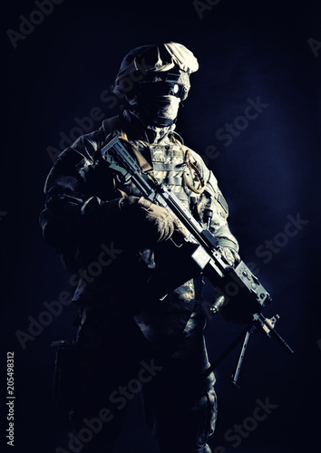 Special operations forces soldier  counter terrorism squad fighter  security service guard  marine shooter in combat uniform  armed with light machine gun low light studio shot on black background