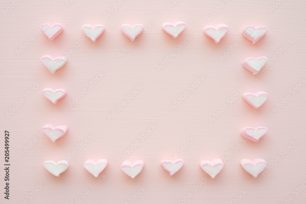 Fluffy pink heart marshmallow frame on pink background from top view
