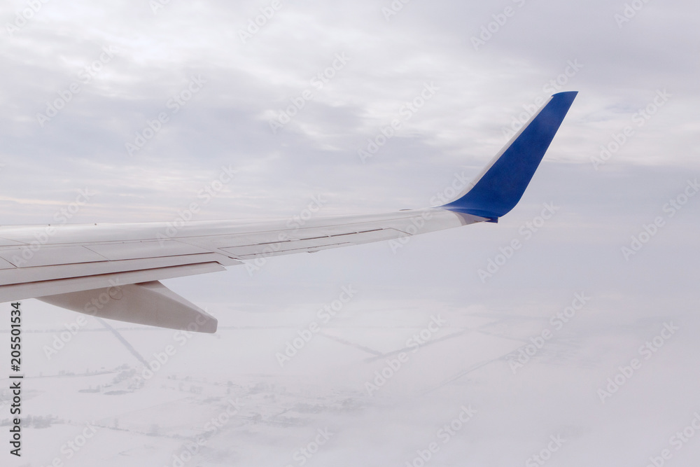 Fototapeta premium wing of aircraft flying above snowy land
