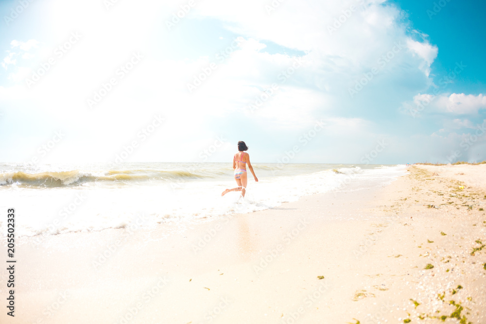A girl is walking along the beach.