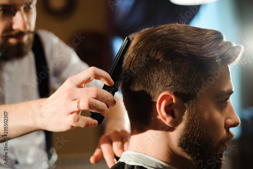 Master cuts hair and beard of men in the barbershop