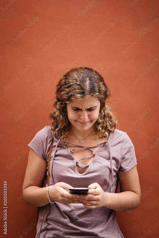 Beautiful young woman with weird face texting on her smart phone Beautiful young woman with weird face texting on her smart phone