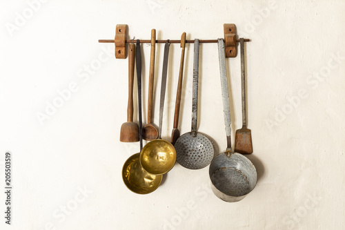 Retro style set of different wooden and metal kitchen spoons and tools hanging on a wall