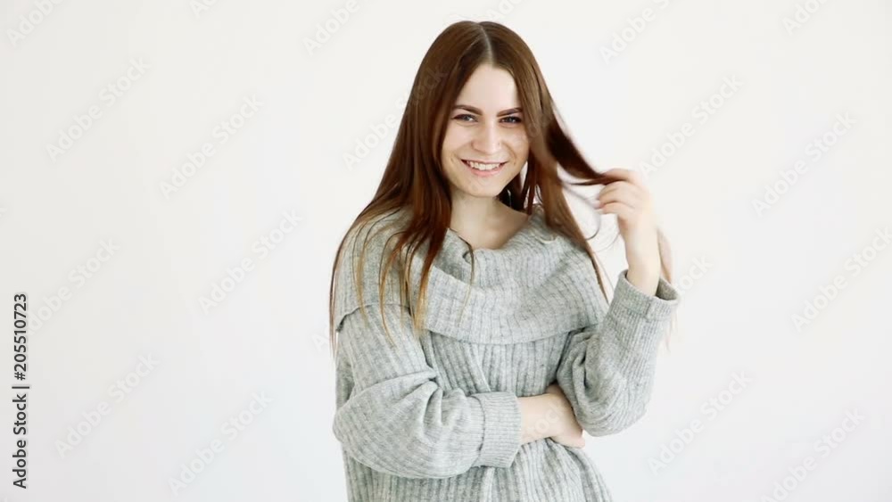 beautiful girl of european appearance in a warm sweater poses against a white wall. emotions - calmness and a smile. beautiful girl of european appearance in a warm sweater poses against a white wall. emotions - calmness and a smile.