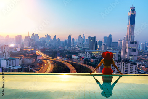 woman enjoy city light in background in swimming pool on rooftop of building