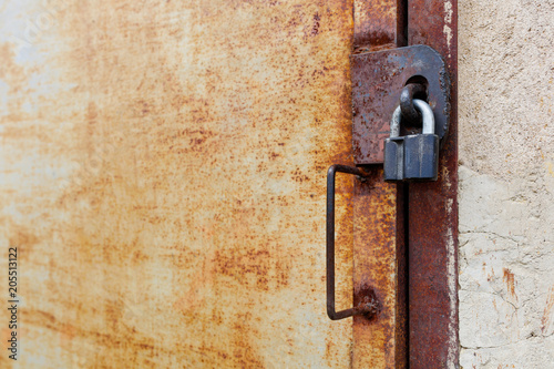 old rusty iron door with padlock and handle, side view close-up