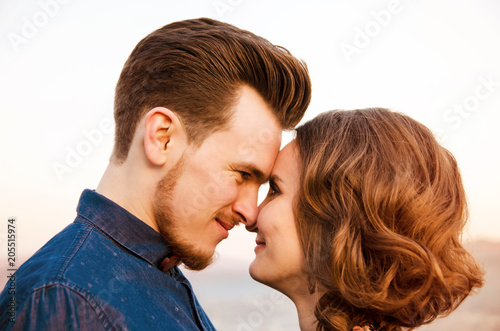 Couple in love look into each other's eyes on background of blur hills. Side view.