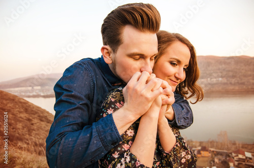 Guy kisses the hands of his beloved girl in the background of the hills and the river. photo