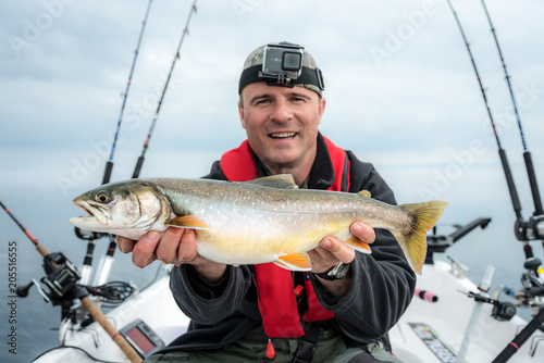 Happy angler with arctic char fishing trophy