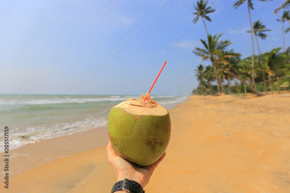 Coconut water in hand on the beach Coconut water in hand on the beach