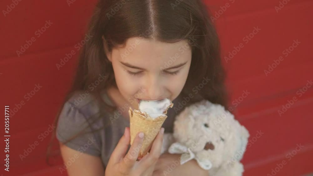 Pretty baby girl kid eating slow motion video lifestyle nursing bottle licking big ice cream in waffle cone with raspberry happy laughing on red background. the girl teenager and ice cream concept Pretty baby girl kid eating slow motion video lifestyle nursing bottle licking big ice cream in waffle cone with raspberry happy laughing on red background. the girl teenager and ice cream concept
