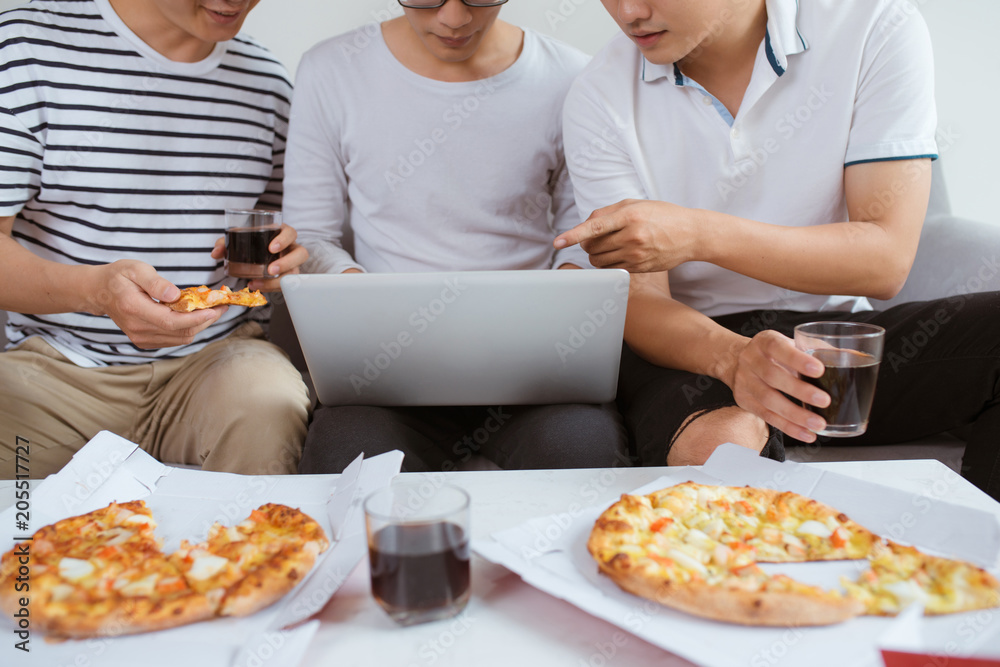 Joyful friends enjoying their pizza while sitting on couch at home. Joyful friends enjoying their pizza while sitting on couch at home.