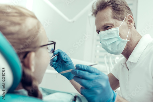 Open your mouth. Careful professional dentist using the instruments while curing his patient