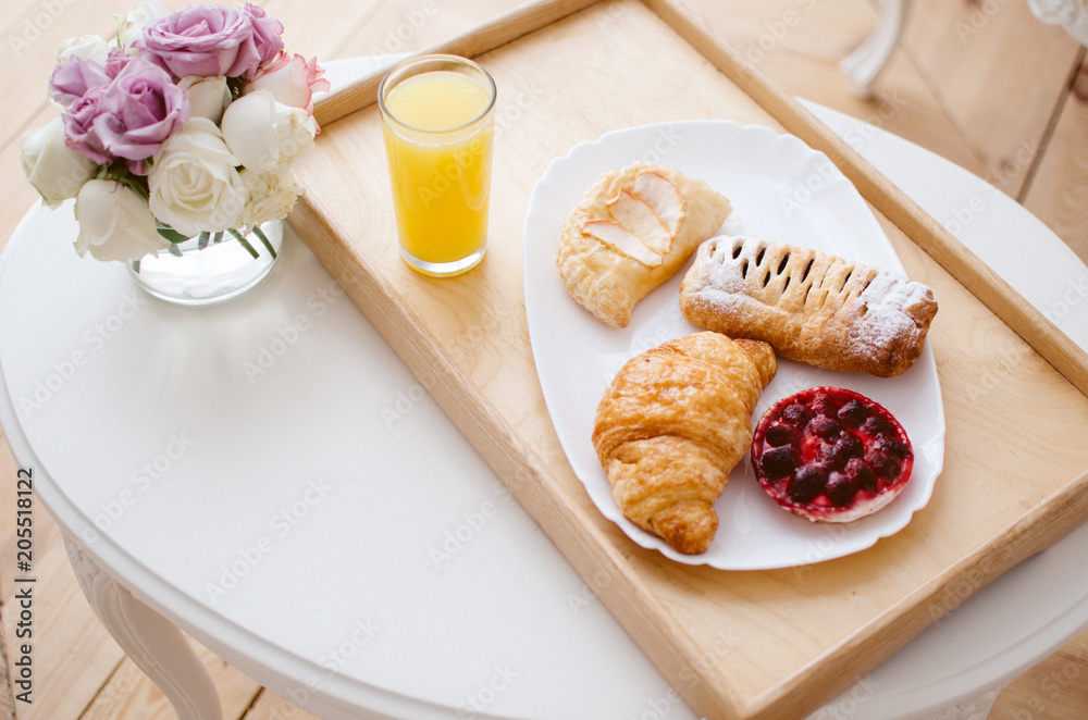 Breakfast in bed on a tray, freshly squeezed juice and croissants