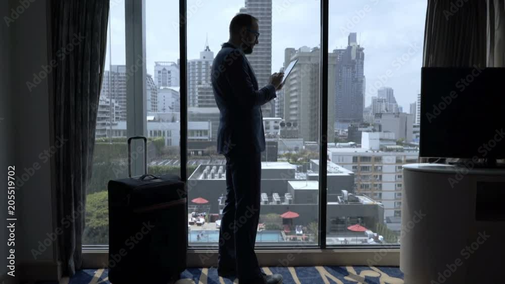 Businessman standing in his hotel room and browsing internet on tablet
Businessman standing in his hotel room and browsing internet on tablet