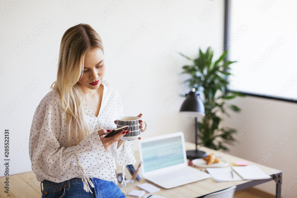 Young woman working in office, taking a break, drinking coffee Young woman working in office, taking a break, drinking coffee