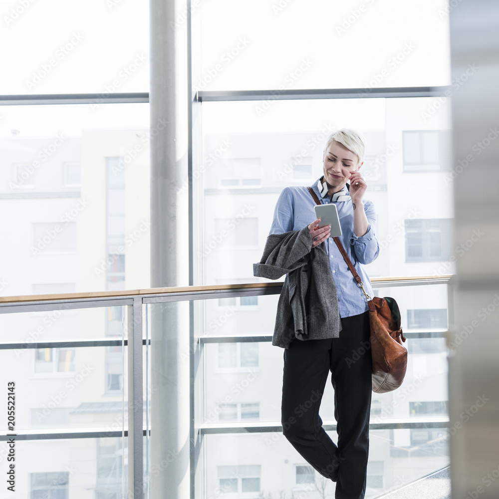 Smiling woman in office building using cell phone Smiling woman in office building using cell phone