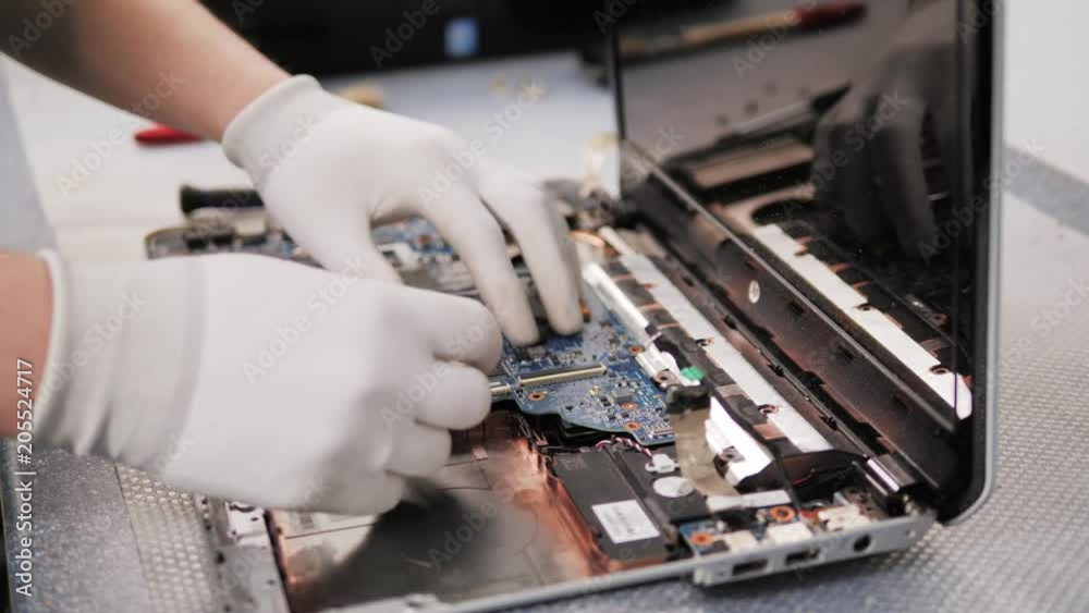Closeup shot of male hands working on disassembling and cleaning circuit board in laptop using brush repair pc processor and change cooler