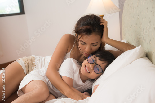 Mother and daughter enjoy in bed at home